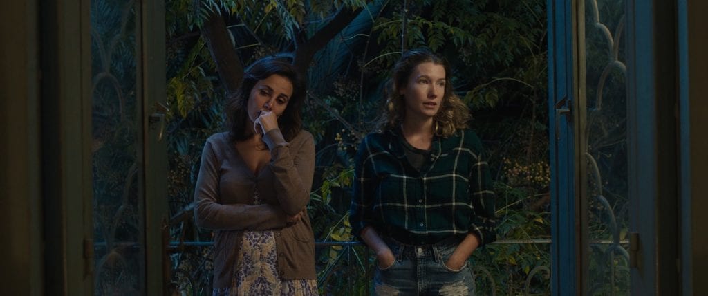 Two women in a dimly lit room looking away from each other
