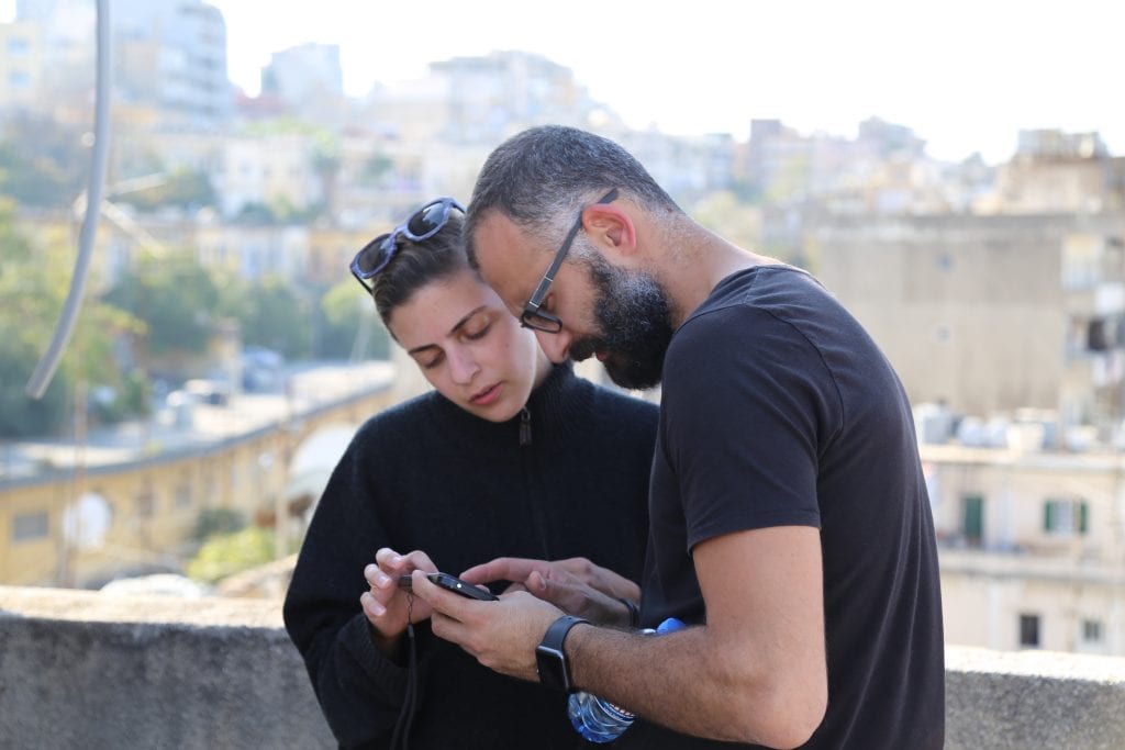 A man and woman looking at a phone with a skyline in the background