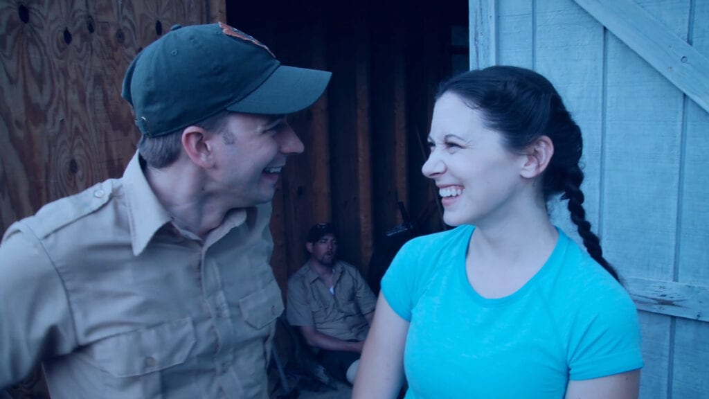 Victor (Chris Young) and Emaline Williams (Katy) stand next to each other laughing. 