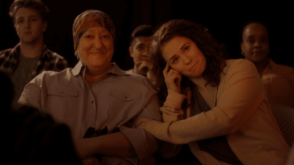 Joy (Carin Silkaitis) and Charlie (Mélisa Breiner-Sanders) sit next to each other in Being Here (directed by Sydney O’Haire).