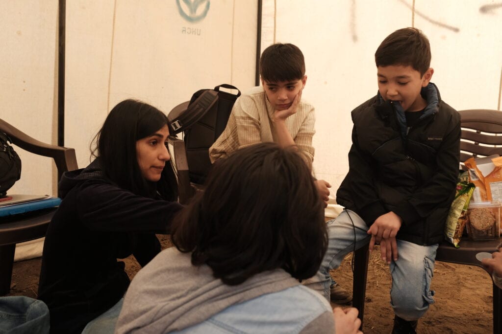 Ragini, the director, is sitting on the ground talking with a few of the child actors in the film.