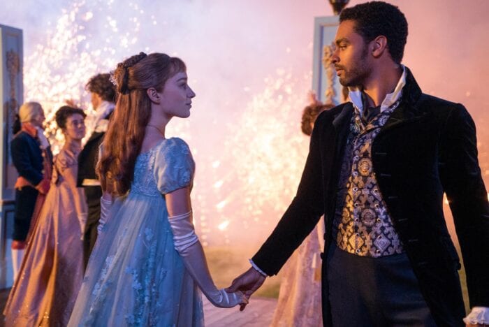 A still from Bridgerton where the main couple is dancing together in regency-inspired clothing. 