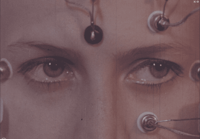 A zoomed in shot of a pair of feminine eyes in a face that has electrodes attached to it.
