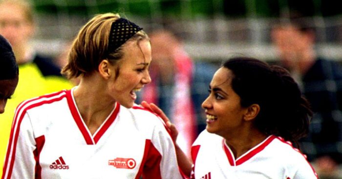 Jules and Jess look at each other, tired and smiling, in matching red-and-white soccer uniforms.